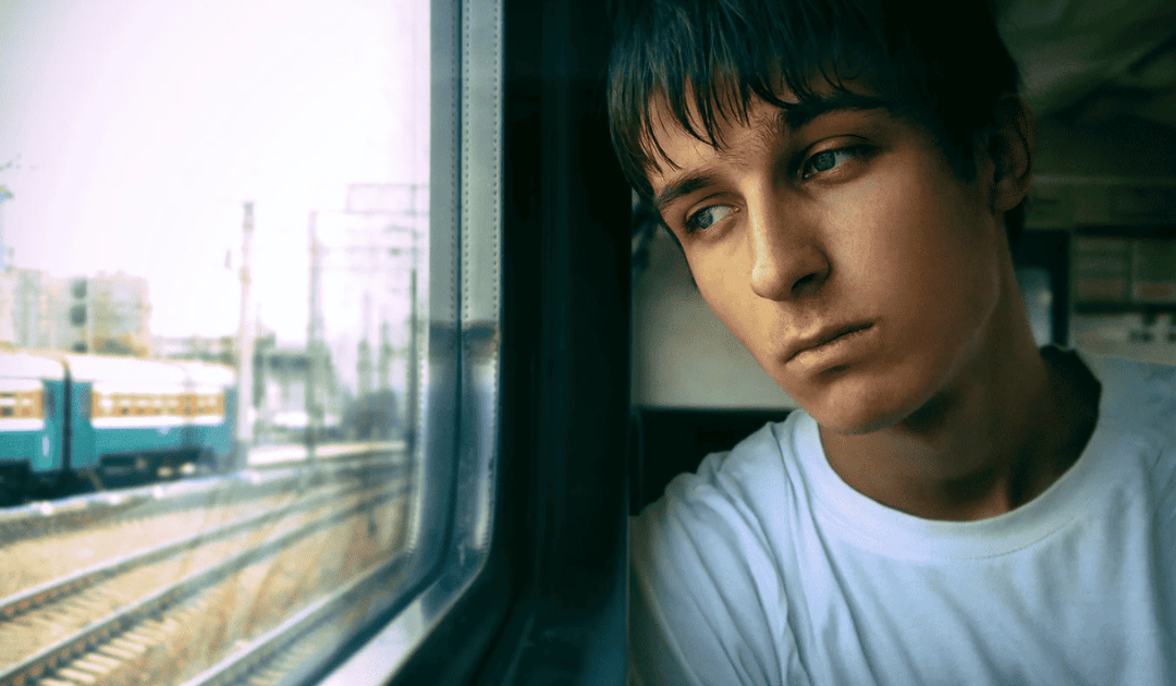 Young man looking nostalgic out of a train window after his Erasmus experience — the feeling of post-Erasmus depression and reverse culture shock Young man looking nostalgic out of a train window after his Erasmus experience — the feeling of post-Erasmus depression and reverse culture shock